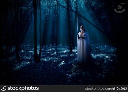 Young elven girl with sword at night forest