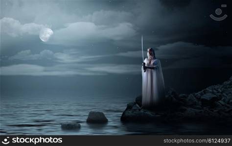 Young elven girl with sword at night sea shore