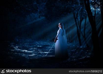 Young elven girl with sword in night forest
