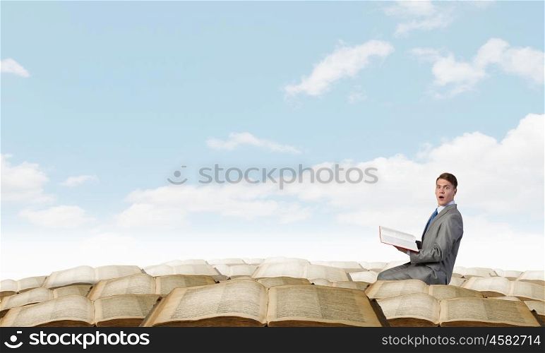 Young emotional businessman with opened book in hand. Young businessman with opened book in hands