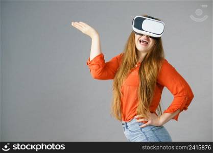 Young emotional woman wearing virtual reality goggles headset, vr box. Connection, technology, new generation and progress concept. Studio shot on gray. Girl wearing virtual reality goggles.