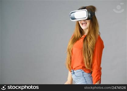 Young emotional woman wearing virtual reality goggles headset, vr box. Connection, technology, new generation and progress concept. Studio shot on gray. Girl wearing virtual reality goggles.