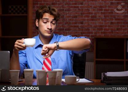 Young employee drinking coffee working at night shift 