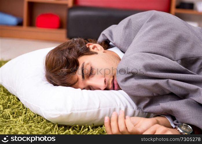 Young employee sleeping on the floor at office 