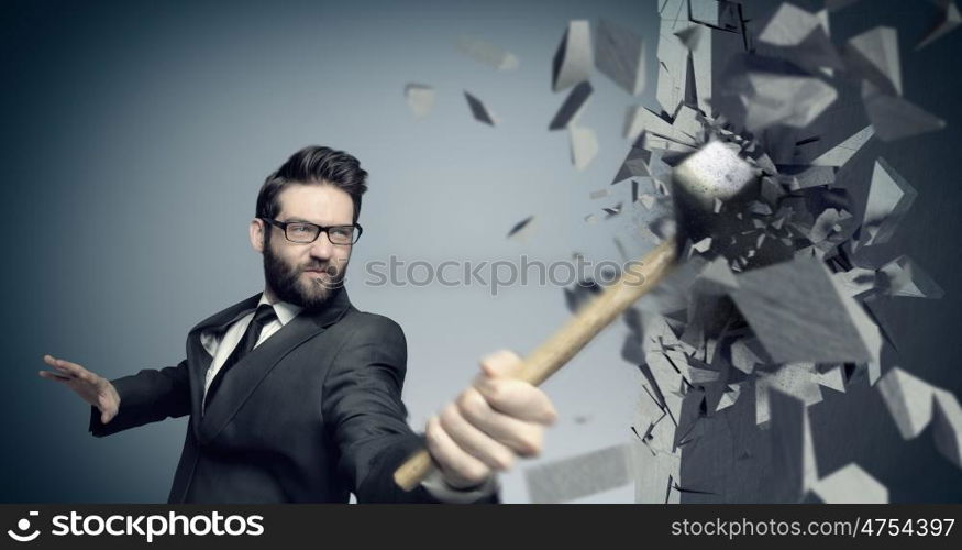 Young employee smashing a wall with a hammer