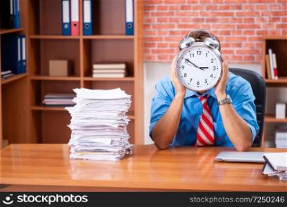 Young employee with excessive work sitting at the office 