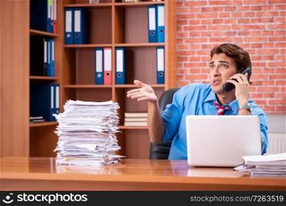 Young employee with excessive work sitting at the office . The young employee with excessive work sitting at the office 