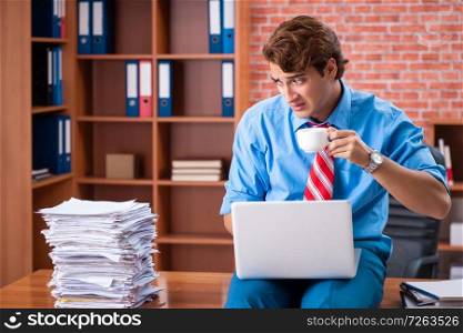 Young employee with excessive work sitting at the office . The young employee with excessive work sitting at the office 