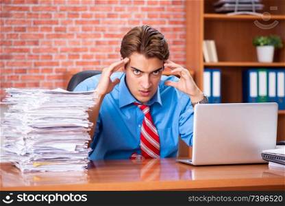 Young employee with excessive work sitting at the office 