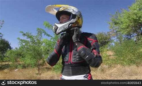 Young enduro racer dressing motorcycle protective gear and riding away jib crane shot