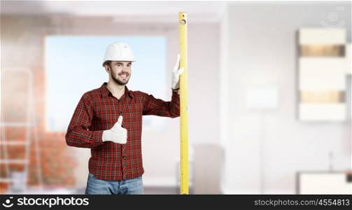 Young engineer man. Builder man in checked shirt using measuring level