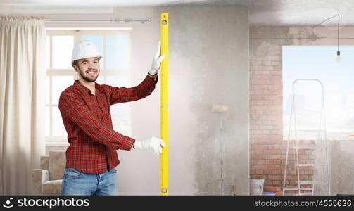 Young engineer man. Builder man in checked shirt using measuring level