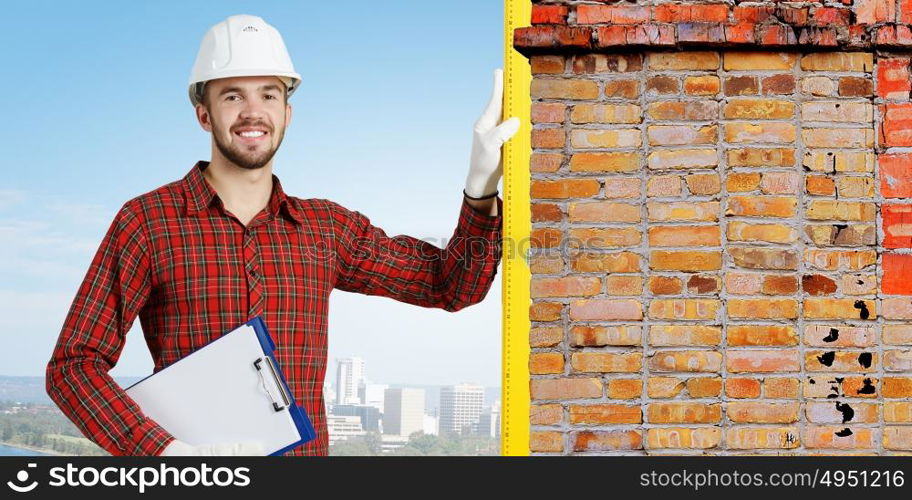 Young engineer man. Builder man in checked shirt using measuring level