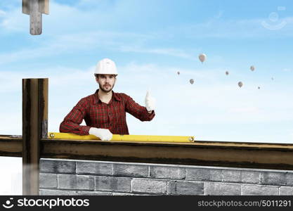 Young engineer man. Builder man in checked shirt using measuring level