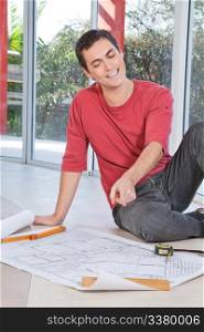 Young engineer smiling and pointing at blueprint