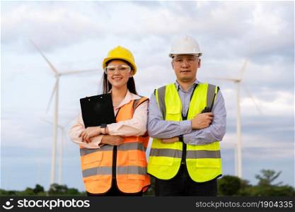 young engineer team working against wind turbine farm