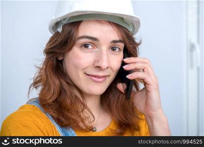 Young engineer woman with a safety helmet talking on phone