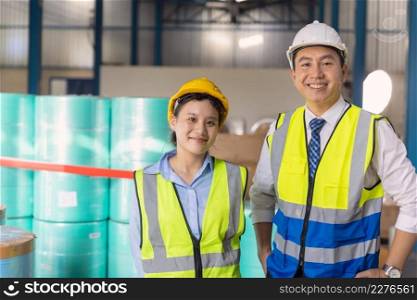 Young engineer working woman standing with adult man worker with safety suit hardhat in factory background