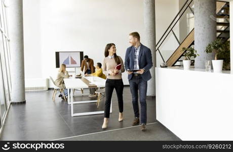 Young entrepreneurs walking together and using digital tablet in the modern office