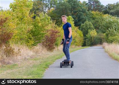 Young european man rides electrical mountainboard on road in nature