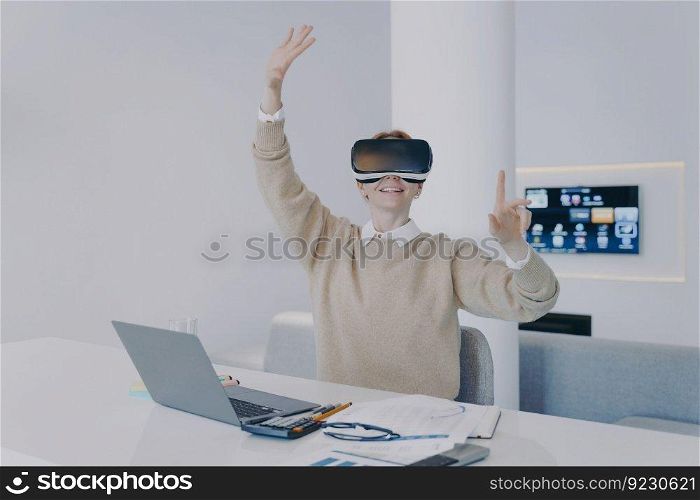 Young european woman in VR headset in office. Student of futuristic college. Girl working on project in cyberspace. Concept of being in virtual reality and simulation in education.. Student in VR headset. Virtual reality and simulation in education. Student of futuristic college.