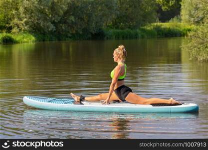Young european woman in yoga posture on SUP in water