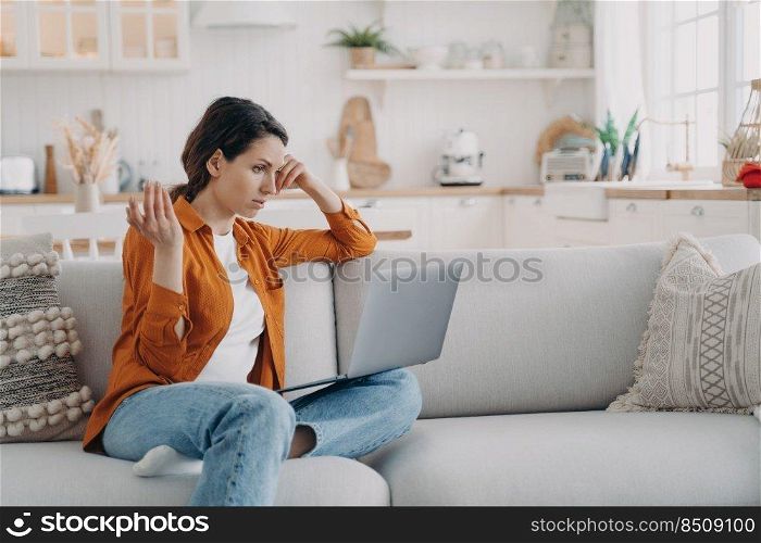 Young european woman is telling problem by video call. Entrepreneur has online conference at home. Girl with laptop is talking at internet meeting. Tired freelancer is working while quarantine.. Young woman is telling problem by video call. Entrepreneur has online conference at home.
