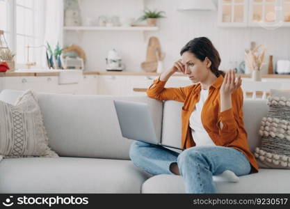 Young european woman is telling problem by video call. Entrepreneur has online conference at home. Girl with laptop is talking at internet meeting. Tired freelancer is working while quarantine.. Young woman is telling problem by video call. Entrepreneur has online conference at home.
