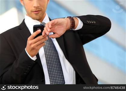 Young executive checking his watch against a cellphone
