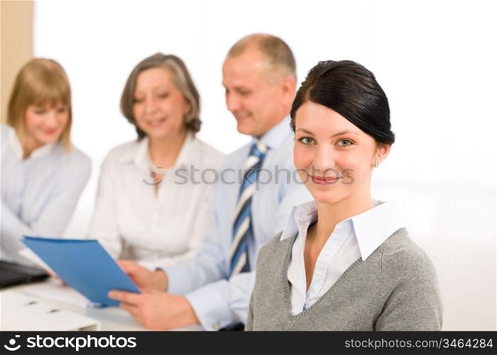 Young executive woman looking camera during meeting with team colleagues