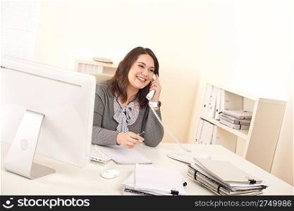 Young executive woman talking on phone at office in front of computer