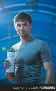 Young exhausted athlete drinking fresh water to refresh during a running trail