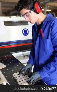 Young factory worker preparing machine