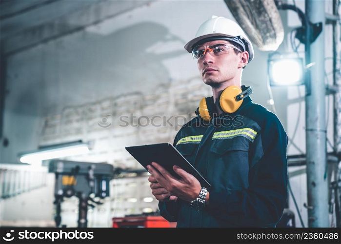 Young factory worker using adept tablet computer in a workshop building . Industrial technology and manufacturing software configuration .. Young factory worker using adept tablet computer in a workshop building