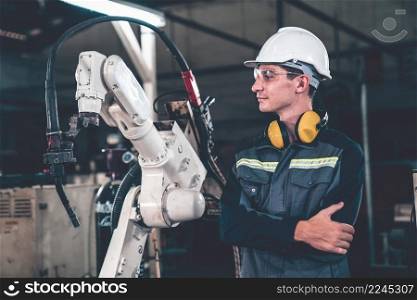 Young factory worker working with adept robotic arm in a workshop . Industry robot programming software for automated manufacturing technology .. Young factory worker working with adept robotic arm