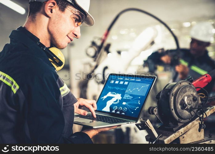 Young factory worker working with adept robotic arm in a workshop . Industry robot programming software for automated manufacturing technology .. Young factory worker working with adept robotic arm