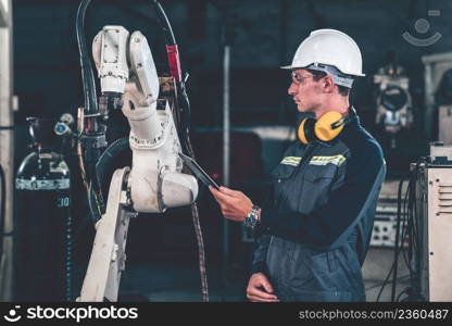 Young factory worker working with adept robotic arm in a workshop . Industry robot programming software for automated manufacturing technology .. Young factory worker working with adept robotic arm