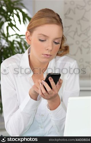 Young fair-haired woman sending text message