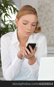 Young fair-haired woman sending text message