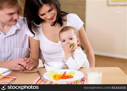 young family at home having meal together with a baby