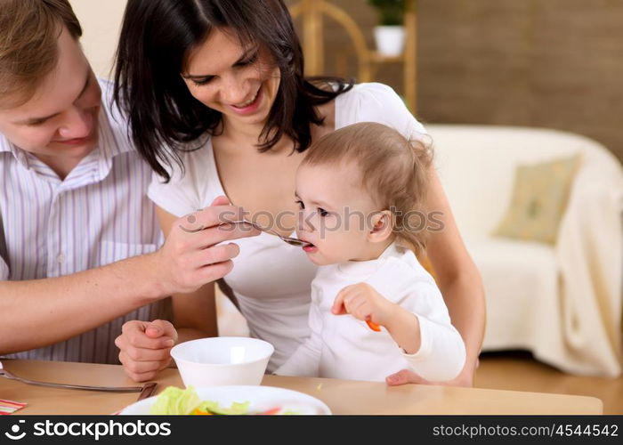 young family at home having meal together with a baby