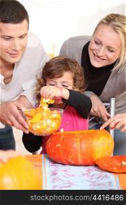 Young family carving hallowe&rsquo;en pumpkins