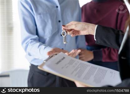 Young family couple getting house key from real estate agent after signed contract agreement home loan