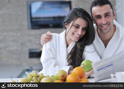young family couple read newspaper at kitchen in morning with fresh breakfast fruits food and coffee drink on table