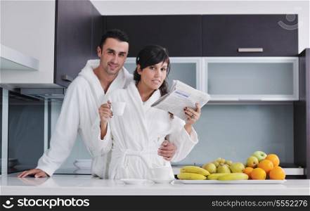 young family couple read newspaper at kitchen in morning with fresh breakfast fruits food and coffee drink on table