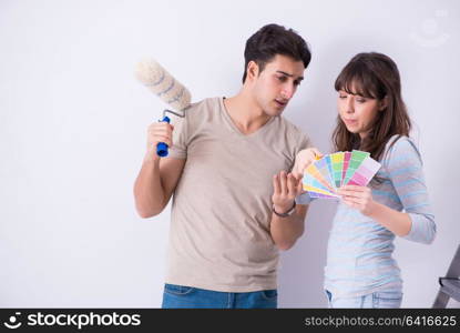 Young family doing renovation at home - painting walls