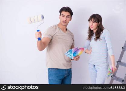 Young family doing renovation at home - painting walls