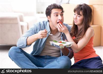 Young family eating food in new apartment after moving in