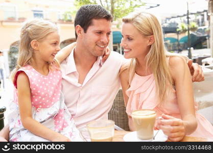 Young Family Enjoying Cup Of Coffee In CafZ Together