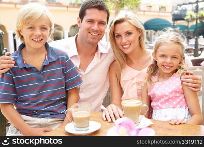 Young Family Enjoying Cup Of Coffee In CafZ Together